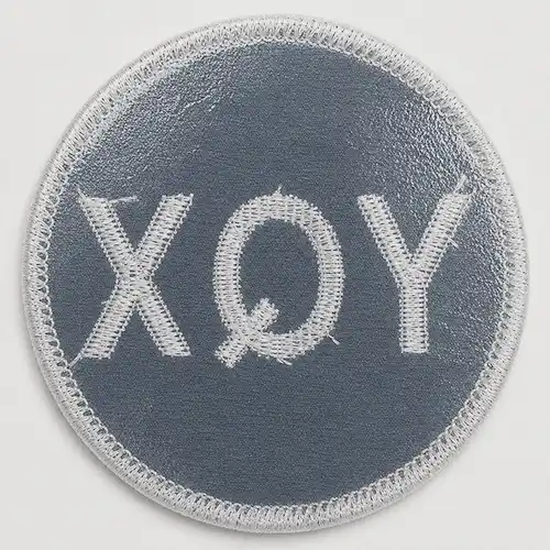 Back view of a custom round embroidered patch with a heat-activated iron-on adhesive backing.
