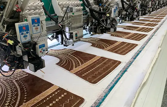 Computerized beading equipment producing decorative embroidered panels with consistent placement and repeatable bulk production quality.
