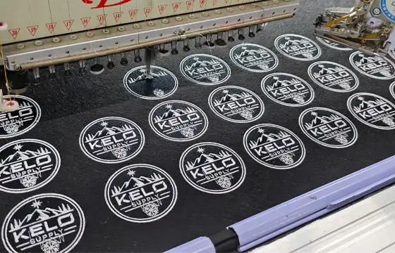 Computerized embroidery machines producing repeated logo patches with consistent stitch detail for bulk embroidery production.