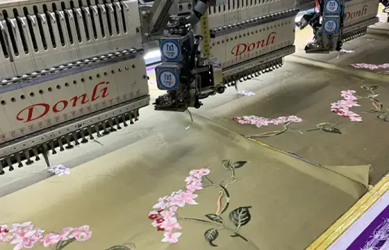 Computerized embroidery machines stitching floral designs on fabric panels for precision embroidery production.