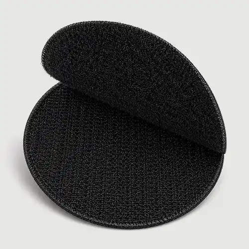 Black round hook-and-loop backing set shown partially separated for removable attachment of a custom embroidered patch.