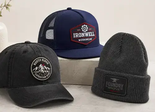 Custom embroidered patches applied to caps and a beanie for branded headwear production.