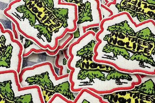 Custom tree-shaped embroidered patches with green, yellow and black stitching and a red embroidered border