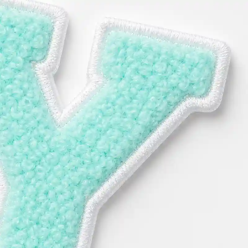 Close-up of a mint green chenille letter patch finished with a clean white embroidered border