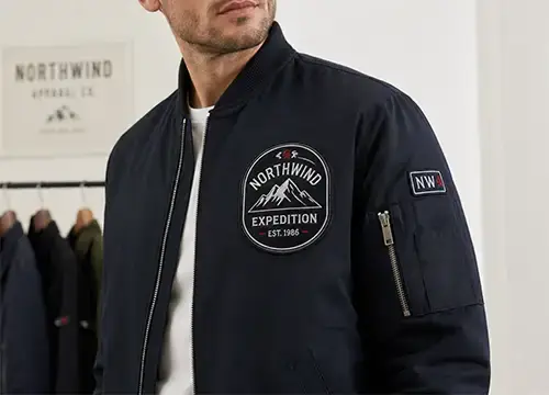 Embroidered patch applied to a jacket chest and sleeve for branded apparel production.
