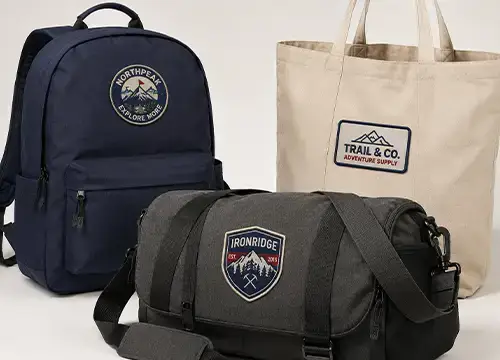 Custom embroidered patches applied to backpacks, duffel bags, and tote bags for branded accessory production.