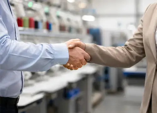 Business handshake in an embroidery factory representing reliable manufacturing cooperation for sourcing partners and multi-buyer projects.