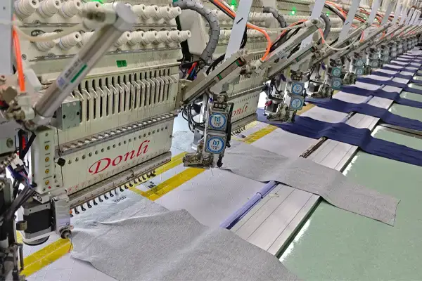 Computerized embroidery machine creating a sample on fabric to check stitch clarity, placement, and quality before bulk production.
