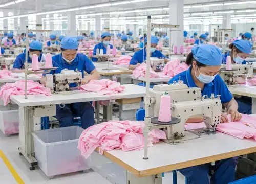 Garment factory workers sewing apparel in bulk production for OEM and ODM manufacturing workflows.