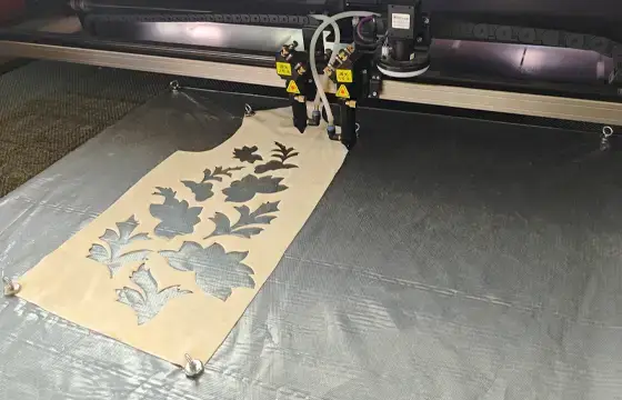 Laser cutting machine cutting shaped fabric components to support precision embroidery production and cleaner finishing.