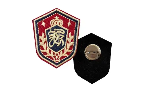 Front and back view of an embroidered patch with safety pin backing for detachable use on badges, events, gifts, or temporary displays.