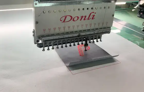 Sampling embroidery machine stitching a small test design to support artwork development and sample approval before bulk production.
