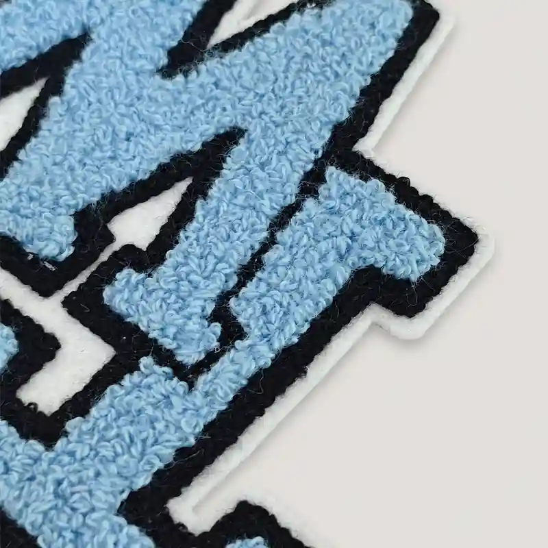 Close-up of a blue chenille patch with black embroidery and a clean single white felt edge
