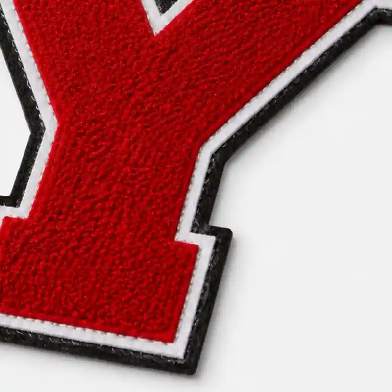 Close-up of a red chenille letter patch with layered white and black triple felt edges
