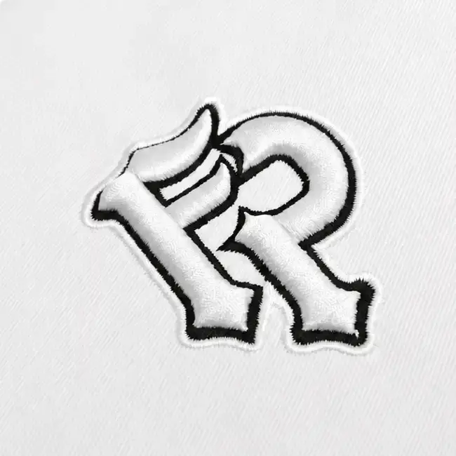 White 3D puff embroidery monogram with black outline stitched on a fashion garment panel.