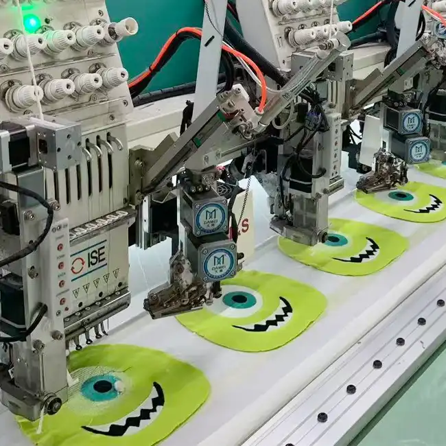 Industrial embroidery machines stitching green cartoon character designs on white handbag fabric panels during bulk production.
