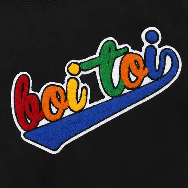 Multicolor chenille embroidery logo stitched onto a black fashion garment panel for textured apparel decoration.