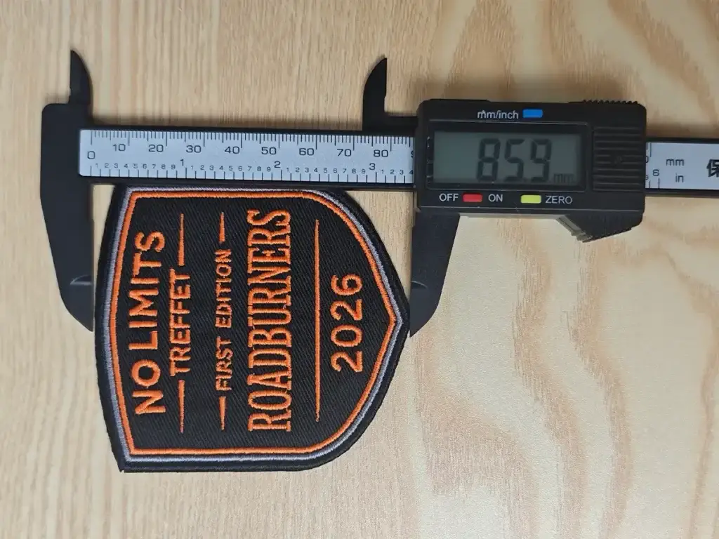 Reference photo of a custom embroidered patch being measured with a digital caliper to confirm final size before embroidery sampling and production review.