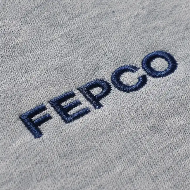 Clean flat embroidery logo reading FEPCO stitched in dark blue thread on a gray fashion garment panel.