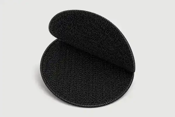 Close-up of black hook and loop backing used for custom embroidered patches, showing the removable attachment system for uniforms, bags, and tactical applications.