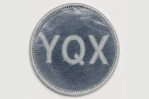 Close-up of a custom embroidered patch with plastic backing, showing the transparent support layer used to provide extra structure and shape stability.
